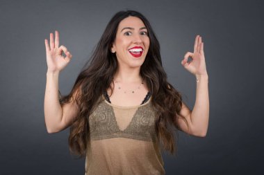 Güzel jestleri olan güzel bir kadın. Gri arkaplanda duruyor. 