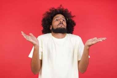 Afro saçlı genç adamın kırmızı duvara karşı kafası karışık. 