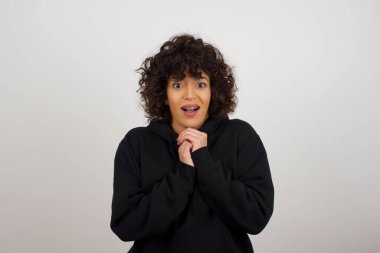 Tatlı yüzlü, rüya gibi, genç bir kadın. Ellerini yüzünün yanında çapraz tutuyor. Hoş bir şey için heyecanlı..