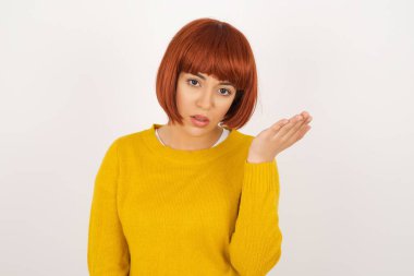 What the hell are you talking about, nonsense. Studio shot of frustrated woman  gesturing with raised palm, frowning, being displeased and confused with dumb question over gray wall.