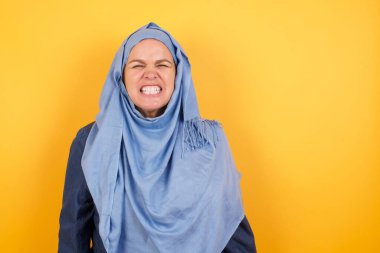 Çatlak, orta yaşlı, tesettürlü Müslüman kadın dişlerini öfkeyle sıkar, gelen sesten rahatsız olur, şık kıyafetler giyer, arka planda izole olur.. 