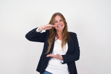 Sarışın, Avrupalı, orta yaşlı bir kadın. Arka planda izole edilmiş. Ellerinde büyük ve büyük boy işareti, ölçü sembolü var. Kameraya bakıp gülümsüyor. Ölçüm konsepti.