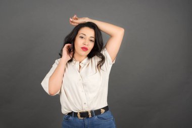 Güzel esmer kadın poz veriyor. Gri arkaplanda duruyor. 