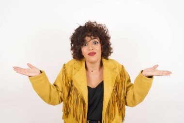 Kafası karışmış, kolları açık genç bir kadın omuzlarını silkip 