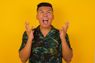 Çığlık, nefret, öfke. Mavi stüdyo arka planında bağıran ağlayan duygusal, öfkeli İspanyol adam. Duygusal, genç yüz. Yarım boy kadın portresi. İnsani duygular, yüz ifadesi kavramı. Moda renkleri