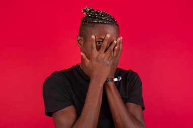 Endişe - Afro-Amerikan bir adamın kavramsal görüntüsü ellerini yüzünü kapatıyor ve parmaklarının bir gözü kapalı dışarı bakıyor. Bir şeyden ya da birinden korktun mu?.