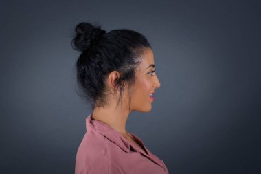 Sağlıklı, saf tenli, gülümseyen bir kadın profili, gür saç stili, düşünceli bir ifadesi var, dışarıda yürümeye hazır, beyaz stüdyo duvarının üzerinde fotokopi alanı ile izole edilmiş.