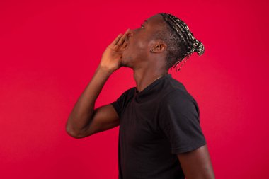 Genç Afrikalı Amerikalı adam sarı arka plan profiline karşı duruyor, mutlu ve heyecanlı görünüyor, bağırıyor ve uzayı kopyalamak için çağırıyor..