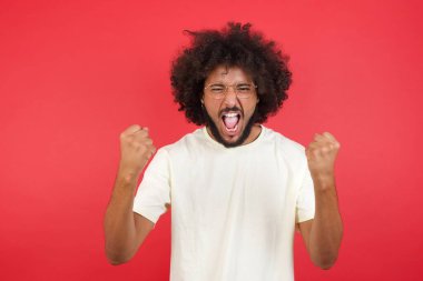 Kızıl duvara bağıran afro saçlı genç adam.   