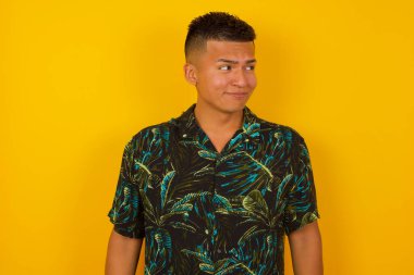 Şaşırmış İspanyol adamın fotoğrafı, kıvrımlı dudaklar ve endişeli bir bakış, önünde korkunç bir şey görüyor, arka planda soyutlanmış, kot tulum giymiş..