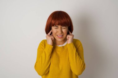 Mutsuz, stresli bir kadın endişeli bir ifade takınıyor, parmaklarıyla kulaklarını tıkıyor, üst katındaki komşulardan gelen gürültüden rahatsız oluyor..