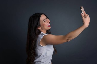 Gri arka planda dururken selfie çeken güzel bir kadın.. 