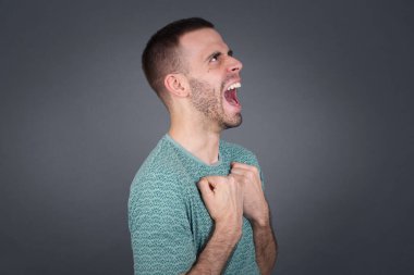 Yakışıklı beyaz adam zafere ulaştığına sevinmiş, heyecanlı, yumruklarını sıkmış, gözleri kapalı çığlıklar atmış, üniversitedeki tüm sınavları geçtiği için mutlu, başarılı biri..