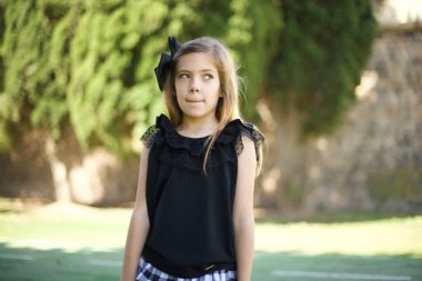 Kafası karışmış, siyah elbiseli tatlı bir kızın fotoğrafı dudaklarını kıvırıyor ve endişeli bir bakış atıyor. Önünde korkunç bir şey görüyor.