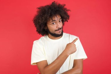 Kızıl duvarı işaret eden afro saçlı genç adam. 