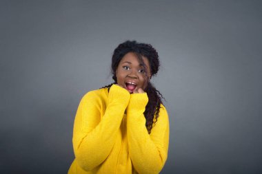 Mutlu Afro-Amerikan kadınlarının gündelik kıyafetleri içinde el ele tutuşmuş, neşeli bir şekilde ertesi gün için arkadaş fikrine benzer, gri duvarda izole bir şekilde. Pozitif duygular.