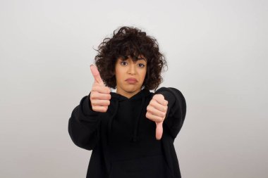 Oldukça düşünceli genç bir kadın iyiye kötüye işaret veriyor. Sıradan kıyafetler giymekten memnun değil ve etkilenmiyor..