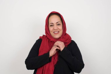 Tatlı yüzlü, hayalperest, olgun Müslüman bir kadın. Ellerini yüzünün yanında çapraz tutuyor. Hoş bir şey için heyecanlı..