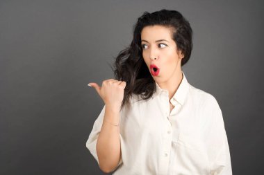 Gri arka planda gelişigüzel giyinmiş güzel esmer kadın..  