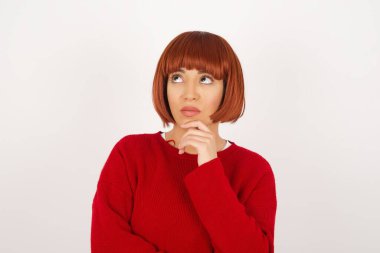 Düşünceli kadın portresi elini çenesinin altında tutuyor, bir şey hatırlamaya çalışıyor ya da ilgi çekici bir şey dinliyor, sıradan giyiniyor, içeride poz veriyor. Gençlik kavramı.