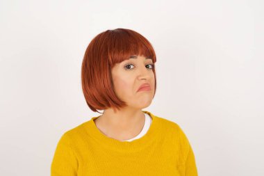 Züppe ifadeli güzel bir kadın dudaklarını kıvırıyor ve kaşlarını kaldırıyor şüpheli ve şüpheci bir ifadeyle şüpheli ve şüpheci bir ifadeyle bakıyor. Gri arka planda kapalı duruyor..