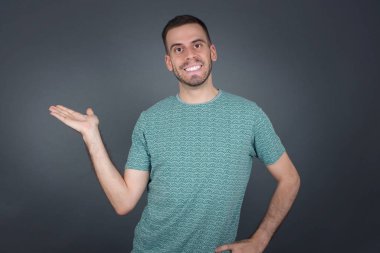 Pozitif memnun erkek der ki: Vay be, ne kadar heyecan verici, hayret verici bir ifade, boş uzayda bir şey gösteriyor, açık elle izole edilmiş gri arkaplan üzerinde. Reklam kavramı.