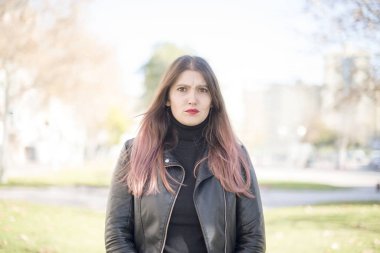 Genç ve güzel bir kadın parkta ciddidir.