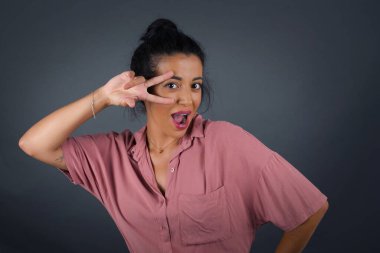 Güzel esmer bir kadın, içeride dikilirken gözlerinde V işareti yapıyor.. 