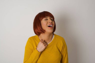 Neşeli bir kadın iyi bir şakaya gülüyor ve eğleniyor ya da gri duvarda dikilerek günlük kıyafetler giyiyor. Mutlu kadın. 