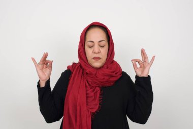 Meditasyon, din ve ruhani uygulamalar. Güzel olgun Müslüman kadın gözlerini kapalı tutuyor, parmaklarını Mudra jestinde tutuyor..
