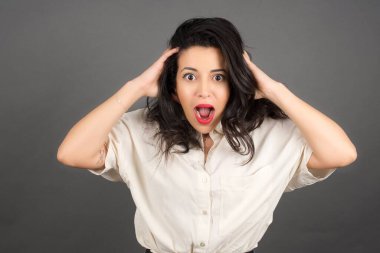 Gündelik giyinmiş güzel esmer kadının gri arka planla kafası karışıyor..  