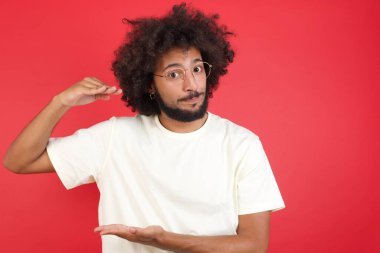 Saçlı genç adam stüdyoda izole edilmiş bir arka planda bir şey gösteriyor. 