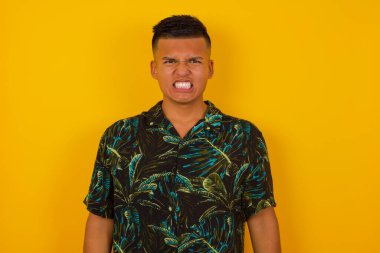 Çılgın İspanyol adam dişlerini öfkeyle sıkar, gelen gürültüden rahatsız olur, modaya uygun kıyafetler giyer, arka planda izole olur. Olumsuz duygu kavramı.