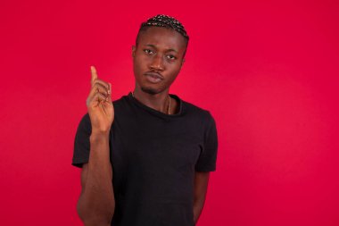 Kırmızı arka plan üzerine siyah tişört giyen Afro-Amerikalı bir adam 