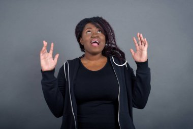 Çığlık, nefret, öfke. Mavi stüdyo arka planında çığlık atan, günlük kıyafetlerle ağlayan kızgın Afrikalı Amerikalı kadın. Duygusal, genç yüz. Yarım boy kadın portresi. İnsani duygular, yüz ifadesi kavramı. Moda renkleri