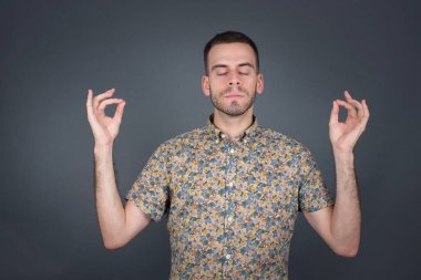 Yakışıklı genç adam sabah uyandıktan sonra evde yoga yapıyor, gözlerini kapalı tutuyor, parmaklarını Mudra jestinde tutuyor.. 