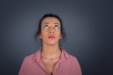 Gizemli esmer kadın portresi gri duvara bakıyor.. 