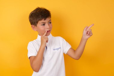 Sarı duvara işaret eden sevimli çocuk.  