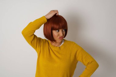 Tüh, ne yaptım ben? Güzel bir kadın korkmuş ve pişmanlık dolu bir ifadeyle el ele tutuşuyor. Gri arka planda dikilen günlük giysiler giyiyor..