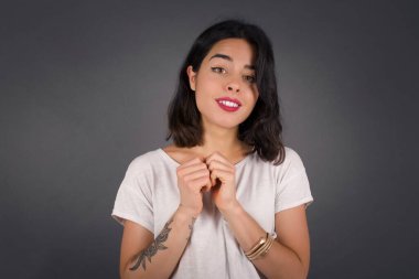 Tatlı yüzlü, rüya gibi, genç bir kadın. Ellerini yüzünün yanında çapraz tutuyor. Hoş bir şey için heyecanlı..