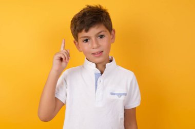 Sarı duvara işaret eden sevimli çocuk.  