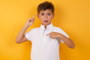 Sarı duvara işaret eden sevimli çocuk.  