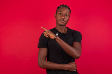 Kamerada poz veren ve el kol hareketi yapan Afro-Amerikan bir gencin portresi. Erkek tasarımcı güzel ürünleri işaret parmağıyla sunuyor. Hareket kavramı.