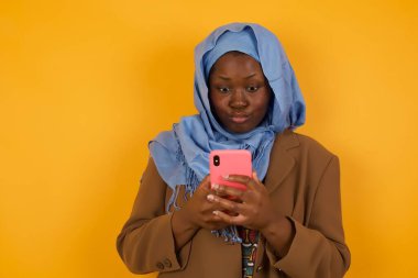 Güzel, Afro-Amerikan Müslüman bir kadının yatay görüntüsü. Gözleri mikroplu, modern akıllı bir telefonu var. Arkadaşından açıklanamayan bir mesaj alıyor..