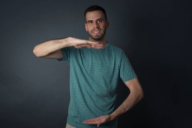 İzole edilmiş arka plan üzerinde gündelik kıyafetler giyen genç ve yakışıklı bir adam. Ellerinde büyük ve büyük bir işaret, ölçü sembolü var. Kameraya bakıp gülümsüyor. Ölçüm konsepti.