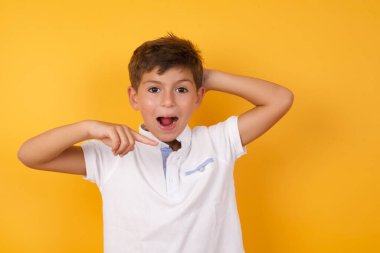Sarı duvara işaret eden sevimli çocuk.  