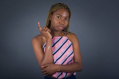 Neşeli genç Afro-Amerikan kadın resmi. Gri duvarın karşısında duruyor. Yüzü birbirine yakın.. 