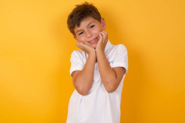 Sarı duvara karşı sevimli mutlu çocuk.  