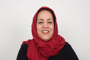 Gülümseyen esmer kadın, geniş gülümsemeli, beyaz dişlerini gösteren, günlük tişört giyen, gri stüdyo duvarının üzerinde duran, izin gününün keyfini çıkaran. İçeride duran bir kadın. Stüdyoda poz veren başörtüsü takan orta yaşlı bir Arap kadın.