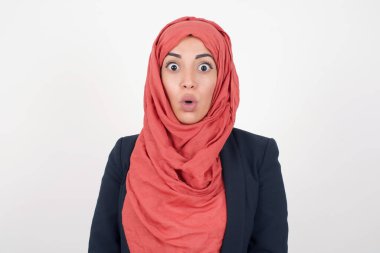 Şaşkın, şaşkın bakışlı, şaşırmış, çığlık atan siyah ceketli ve tesettürlü güzel bir kadın. Şok olmuş bir bakışla kameraya bakıyor.